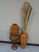 A wicker plant stand and two wooden vases one containing reeds