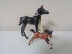 Two Beswick foals, one in black and one in brown.