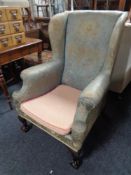 An antique wing backed armchair on claw and ball feet in floral fabric