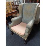 An antique wing backed armchair on claw and ball feet in floral fabric