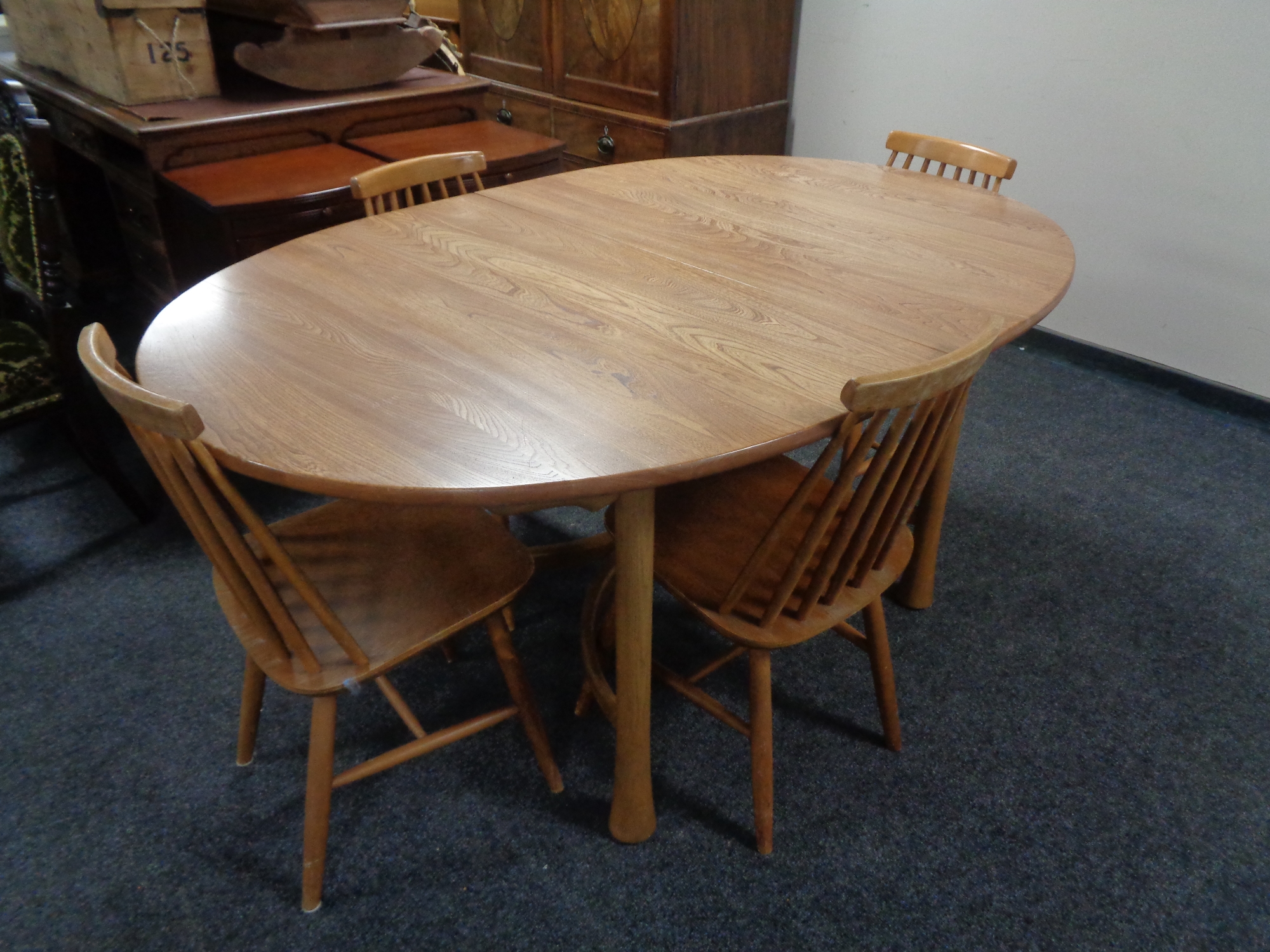 An Ercol elm extending kitchen table and set of four rail backed chairs