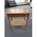 A stripped pine two drawer side table 63 cm x 42 cm x 69 cm.