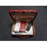 A red leather travel case containing paper ephemera, pens, note paper,
