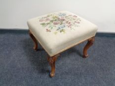 An antique tapestry footstool on cabriole legs