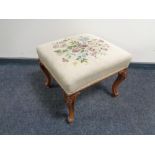 An antique tapestry footstool on cabriole legs