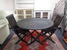 A circular teak folding garden table and two chairs