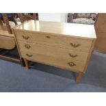 A blonde oak three drawer chest with brass drop handles