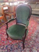 An antique wooden framed armchair in green fabric