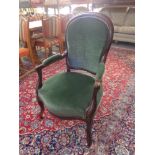 An antique wooden framed armchair in green fabric