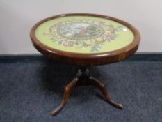 An antique mahogany pedestal wine table with tapestry panel top