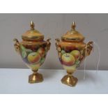 A pair of Coalport porcelain urn shaped lidded vases painted with panels of fruit by M.