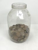 A large glass jar containing a quantity of coins - copper pennies, three pence pieces etc.