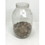 A large glass jar containing a quantity of coins - copper pennies, three pence pieces etc.