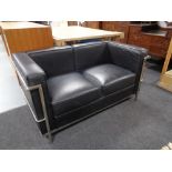 A contemporary black leather and metal two seater settee