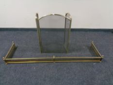 A large brass fender together with a three way folding brass spark guard