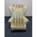A wingback armchair in gold stripped fabric