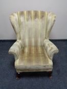 A wingback armchair in gold stripped fabric