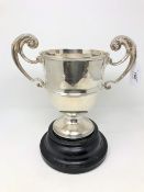 An Edwardian silver twin-handled trophy cup, Chester 1902, height 22cm, on turned ebonised plinth.