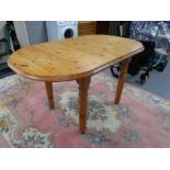 An oval pine extending kitchen table with a leaf