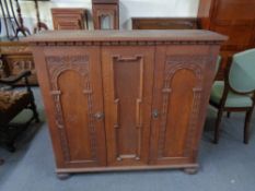A 20th century carved double door cabinet on bun feet