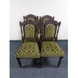A set of four carved Edwardian dining chairs in green fabric
