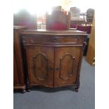 An antique mahogany serpentine fronted cabinet fitted a drawer