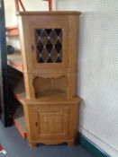 A blonde oak corner cabinet