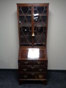 A Victorian inlaid mahogany bureau bookcase on bracket feet fitted with four drawers and brass drop