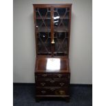 A Victorian inlaid mahogany bureau bookcase on bracket feet fitted with four drawers and brass drop