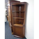 An Ercol elm corner cabinet fitted with shelves