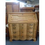 A blonde oak serpentine fronted bureau