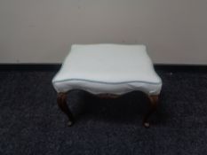 An antique mahogany footstool on cabriole legs