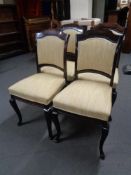 A set of four stained beech dining chairs upholstered in a yellow fabric