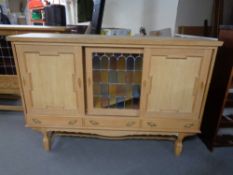 A blond oak sideboard fitted three cupboards and drawers