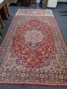 A red floral woolen carpet and similar fringed rug