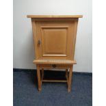 A blonde oak cabinet on raised legs