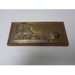 A copper embossed plaque of a steam train mounted on board