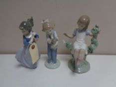 A Lladro figure - Girl seated in tree together with two other Nao figures