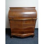 A walnut serpentine fronted barrel bureau