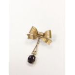 A 9ct gold ribbon shaped bar brooch with garnet drop CONDITION REPORT: 3.