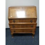 A 1930's walnut bureau fitted with three drawers