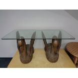 A rectangular glass topped coffee table on a pair of hardwood swan supports