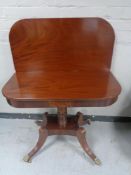 A reproduction mahogany turnover top tea table on four way pedestal