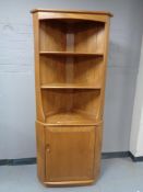 An Ercol elm corner cupboard fitted with shelves above