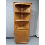 An Ercol elm corner cupboard fitted with shelves above