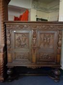 A heavily carved oak double door sideboard on raised legs