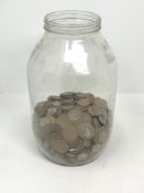 A large glass jar containing a quantity of coins - copper pennies, three pence pieces etc.