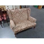 A 20th century wing back settee in pink dralon