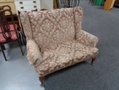 A 20th century wing back settee in pink dralon