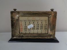 An Edwardian silver fronted scrolling desk calendar